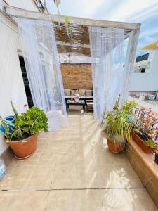 a patio with white curtains and potted plants at Sweet Atic in Sitges