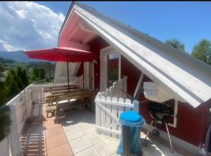 Cette maison dispose d'une terrasse avec un parasol rouge. dans l'établissement Faakersee Seahouse mit Privat Strand -Only Sa-Sa, à Faak am See