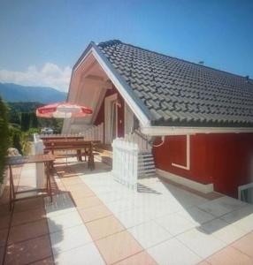 une maison avec une table et un banc sur une terrasse dans l'établissement Faakersee Seahouse mit Privat Strand -Only Sa-Sa, à Faak am See