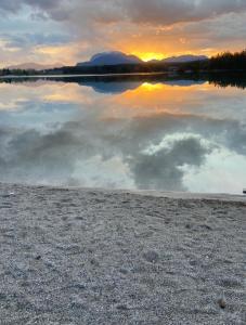 une grande étendue d'eau avec un coucher de soleil en arrière-plan dans l'établissement Faakersee Seahouse mit Privat Strand -Only Sa-Sa, à Faak am See