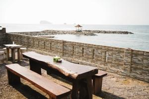 un banc en bois assis à côté d'un mur de briques près de l'océan dans l'établissement Temple Cafe & Cottages, à Candidasa