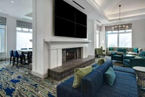 uma sala de estar com um sofá azul e uma lareira em Hilton Garden Inn Detroit Metro Airport em Romulus