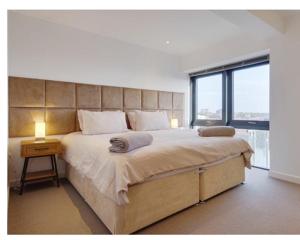 ein Schlafzimmer mit einem großen Bett und einem großen Fenster in der Unterkunft Beach Penthouse Apartment Bournemouth in Bournemouth