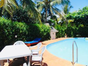 - une piscine avec des chaises, une table, une table et des chaises dans l'établissement Villas Dora and Holly, à Diani Beach