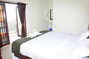 - une chambre avec un grand lit blanc et une fenêtre dans l'établissement Summer Dreams Cottage Kodaikanal, à Kodaikānāl