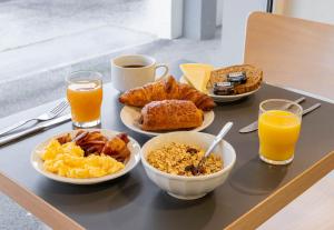 uma bandeja de pequeno-almoço com alimentos de pequeno-almoço e sumo de laranja em B&B HOTEL CALAIS Coquelles Tunnel sous La Manche em Coquelles