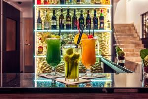 três cocktails sentados num bar com uma prateleira de garrafas em CityClass Hotel Alter Markt em Colónia