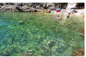 un groupe de personnes dans l'eau d'une plage dans l'établissement APARTMANI KRAJ, à Mošćenička Draga