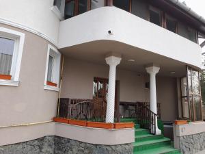 a building with a porch with green stairs and columns at Pensiunea Crown Royal in Alba Iulia