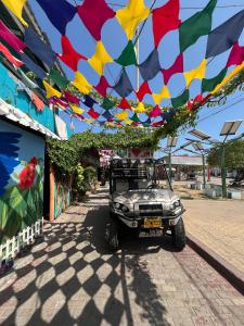 um velho jipe estacionado sob um arco colorido com bandeiras em Posada Amaripucci em San Andrés