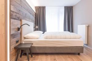 a bedroom with a bed and a wooden wall at Hotel Wieser in Campo di Trens