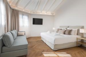 - une chambre blanche avec un lit et un canapé dans l'établissement The Residence Aiolou Hotel & Spa, à Athènes