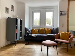 uma sala de estar com um sofá preto e duas cadeiras em Stilvolles Appartement im Herzen Bambergs em Bamberg