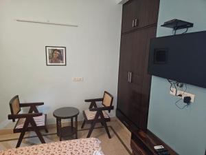 een kamer met een tafel en stoelen en een televisie bij Sky Bloom Luxury Homestay in New Delhi