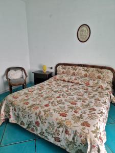 a bed with a floral comforter and a clock on the wall at Agriturismo Fuoco D'Amalfi Villa Iazzetta in Amalfi