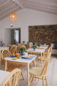 una sala da pranzo con tavoli, sedie e un muro in pietra di Pure Fonte Velha B&B a Vila do Bispo