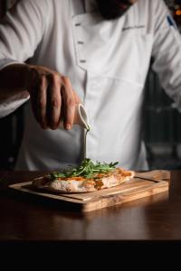 un chef prépare une pizza sur un plateau de découpe dans l'établissement The Residence Aiolou Hotel & Spa, à Athènes