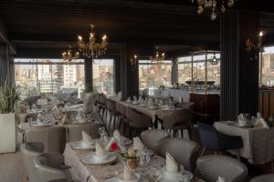 un restaurant avec des tables blanches, des chaises et des fenêtres dans l'établissement Melissa Hotel, à Oran