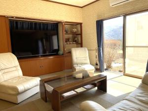 - un salon avec 2 chaises, une table et une télévision dans l'établissement Nikko World Heritage STAY【日光山内】一棟丸貸しの宿, à Nikkō