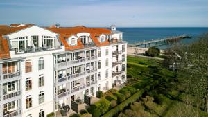 um edifício branco junto ao oceano com um cais em Haus Atlantik em Kühlungsborn