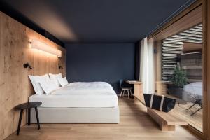 - une chambre avec un lit blanc et un mur bleu dans l'établissement Hotel Lamm, à Castelrotto