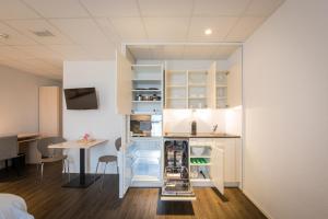 a kitchen with white cabinets and a table in a room at Los Lorentes Apartments Bern Airport in Belp