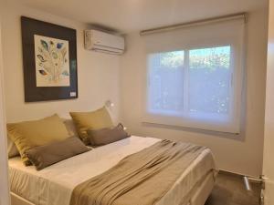 1 dormitorio con 1 cama grande y ventana en Be mas apartamentos boutique Villa Gral Belgrano, en Villa General Belgrano