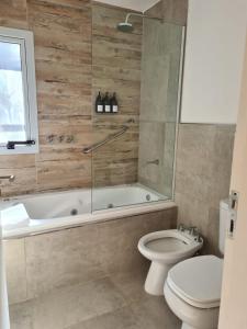 y baño con bañera, aseo y ducha. en Be mas apartamentos boutique Villa Gral Belgrano, en Villa General Belgrano