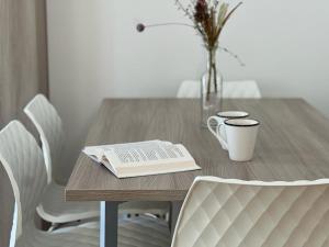 una mesa de madera con un libro y un jarrón de flores en Bernina Suites - vicino al Bernina Express, en Tirano