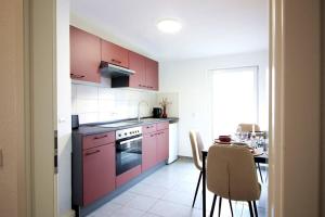 una cucina con armadi rosa e un tavolo con sala da pranzo di Blossfeld-Apartments XL-Ferienwohnung Jena Zentrum, 2 Schlafzimmer, W-Lan, Waschtrockner, Smart-TV a Jena