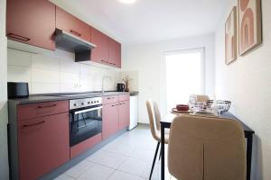 una cucina con armadi rossi e un tavolo con sedie di Blossfeld-Apartments XL-Ferienwohnung Jena Zentrum, 2 Schlafzimmer, W-Lan, Waschtrockner, Smart-TV a Jena