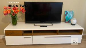 チューリッヒにあるH2 with 3,5 rooms, 2BR, living room and kitchen, central and quiteの白いエンターテイメントセンターの花のテレビ付き