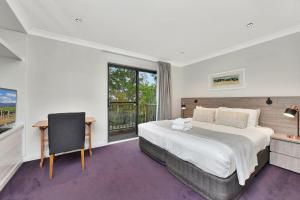 a bedroom with a bed and a desk and a window at Villa 3br Chardonnay Villa located within Cypress Lakes Resort in Pokolbin