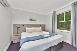 a white bedroom with a large bed and a window at Villa 3br Chardonnay Villa located within Cypress Lakes Resort in Pokolbin