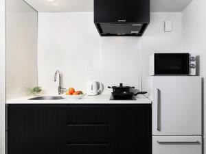 a kitchen with black cabinets and a white refrigerator at MIMARU Osaka Shinsaibashi West in Osaka