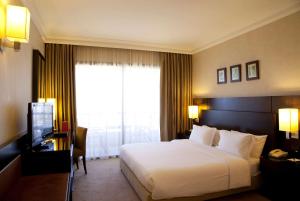 ein Hotelzimmer mit einem Bett und einem TV in der Unterkunft Ramada Plaza by Wyndham Beirut Raouche in Beirut