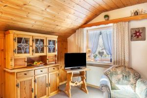 sala de estar con TV y escritorio con silla en Ferienwohnung Lisa Suitner, en Mittenwald