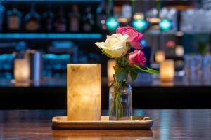 un jarrón con rosas y una vela sobre una mesa en Hotel Royal, en Noordwijk