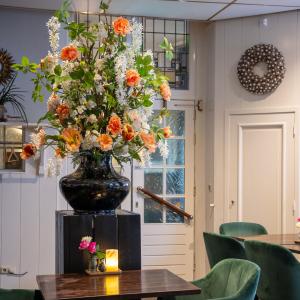 un jarrón grande lleno de flores naranjas y blancas sobre una mesa en Hotel Royal, en Noordwijk