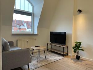 sala de estar con TV, silla y mesa en RAHA Apartments - Modernes Studio-Apartment - am HBF - kostenloser Parkplatz, en Erfurt