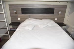 a large white bed with two pillows on it at Hotel du Triangle in Talange