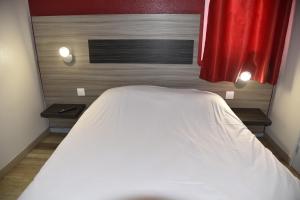 a white bed in a room with a red curtain at Hotel du Triangle in Talange