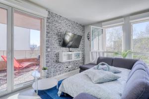 a living room with a couch and a tv on a brick wall at "Le Sérénity ", Appartement spacieux ,balcon, parking privé gratuit, proche CDG et Stade de France in Stains