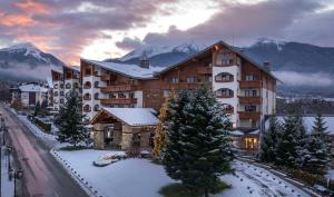 ein großes Gebäude im Schnee mit Bergen im Hintergrund in der Unterkunft Kempinski Hotel Grand Arena Bansko in Bansko