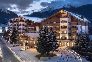 ein Gebäude im Schnee mit Bergen im Hintergrund in der Unterkunft Kempinski Hotel Grand Arena Bansko in Bansko