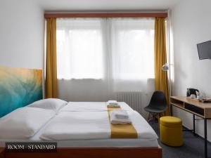 um quarto com uma cama, uma secretária e uma janela em Hotel AMITY em Praga