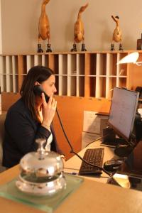 une femme assise à un bureau parlant sur un téléphone portable dans l'établissement Residenza Agnello D'Oro, à Bussolengo