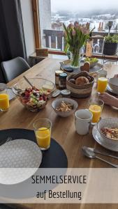 - une table en bois avec des aliments pour le petit-déjeuner et du jus d'orange dans l'établissement Ferienwohnung Alpenflair mit Pool und Sauna & direkt am Skilift, à Missen-Wilhams