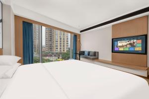 een slaapkamer met een groot bed en een flatscreen-tv bij Fairfield by Marriott Changsha Yuelu in Changsha