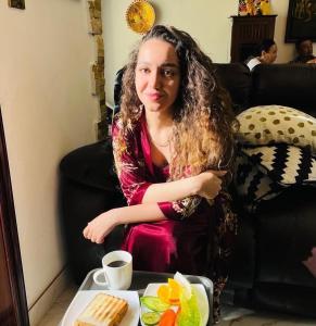 une femme assise à une table avec une assiette de nourriture dans l'établissement Dreams beach hostel, à Dubaï